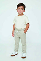 Cream waffle-knit baby trousers on model, straight fit with drawstring waist and cuffs