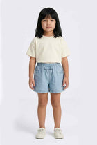 Light blue denim baby girl shorts with elastic waistband, worn with cream top