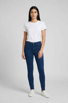 Mid-blue skinny jeans on model, straight slim legs with ankle-length hem