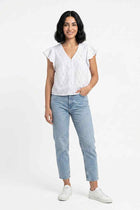 White embroidered blouse with short ruffle sleeves, V-neck, and button front worn by model