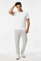 Light gray men’s jogger trousers on model, drawstring waist and tapered elastic cuffs