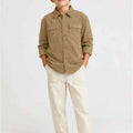 Brown boys corduroy button-down shirt on boy, front view with chest pockets