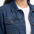 Mid-blue denim jacket close-up of chest flap pockets, metal buttons, and stitching.