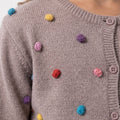 GirlsÃ¢â‚¬â„¢ grey knit cardigan with colorful pom-pom trim and buttoned placket.