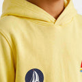 Yellow boys hoodie close-up with circular sailboat patch and stitched hood seam