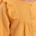 Mock orange blouse detail: ruffled collar, button placket, and textured long sleeves