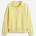 Women's pale yellow polo sweatshirt with embroidered chest text, long sleeves