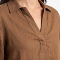 Brown button-up shirt close-up: collared V neckline and chest pocket detail.