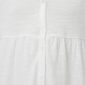 Close-up of white dress front: V-neck with buttons and tiered skirt paneling